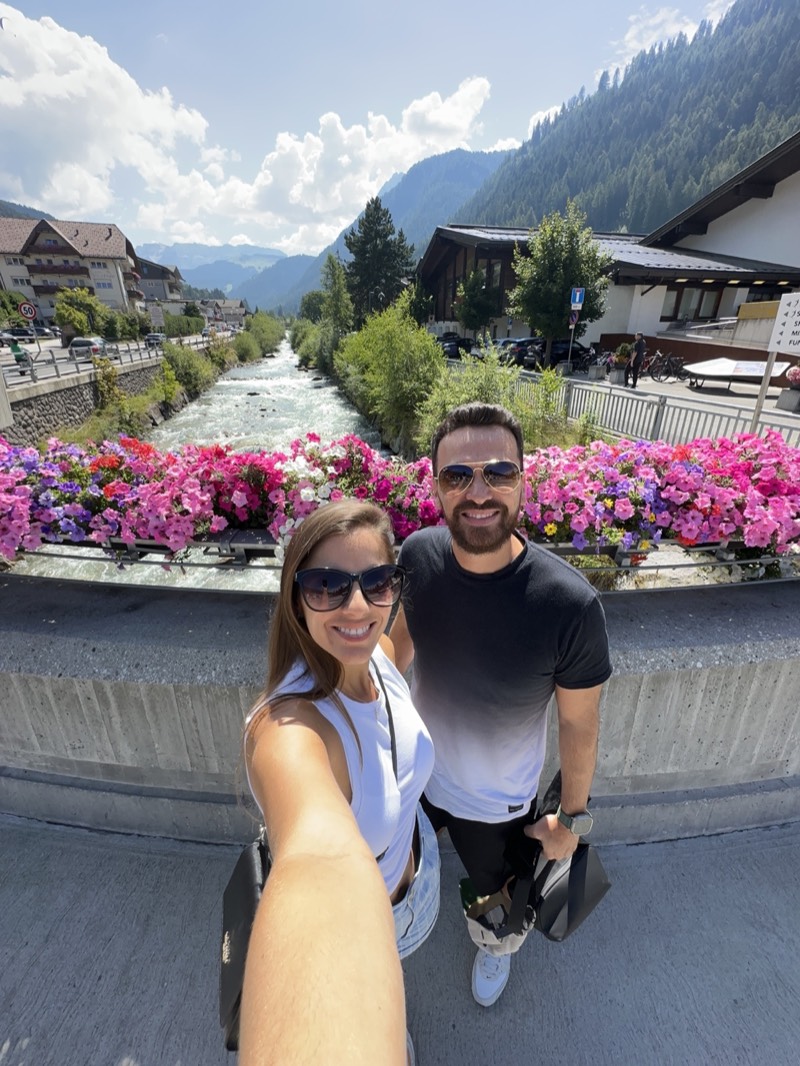 Léo e Patrícia em Ortisei diante do rio e das montanhas